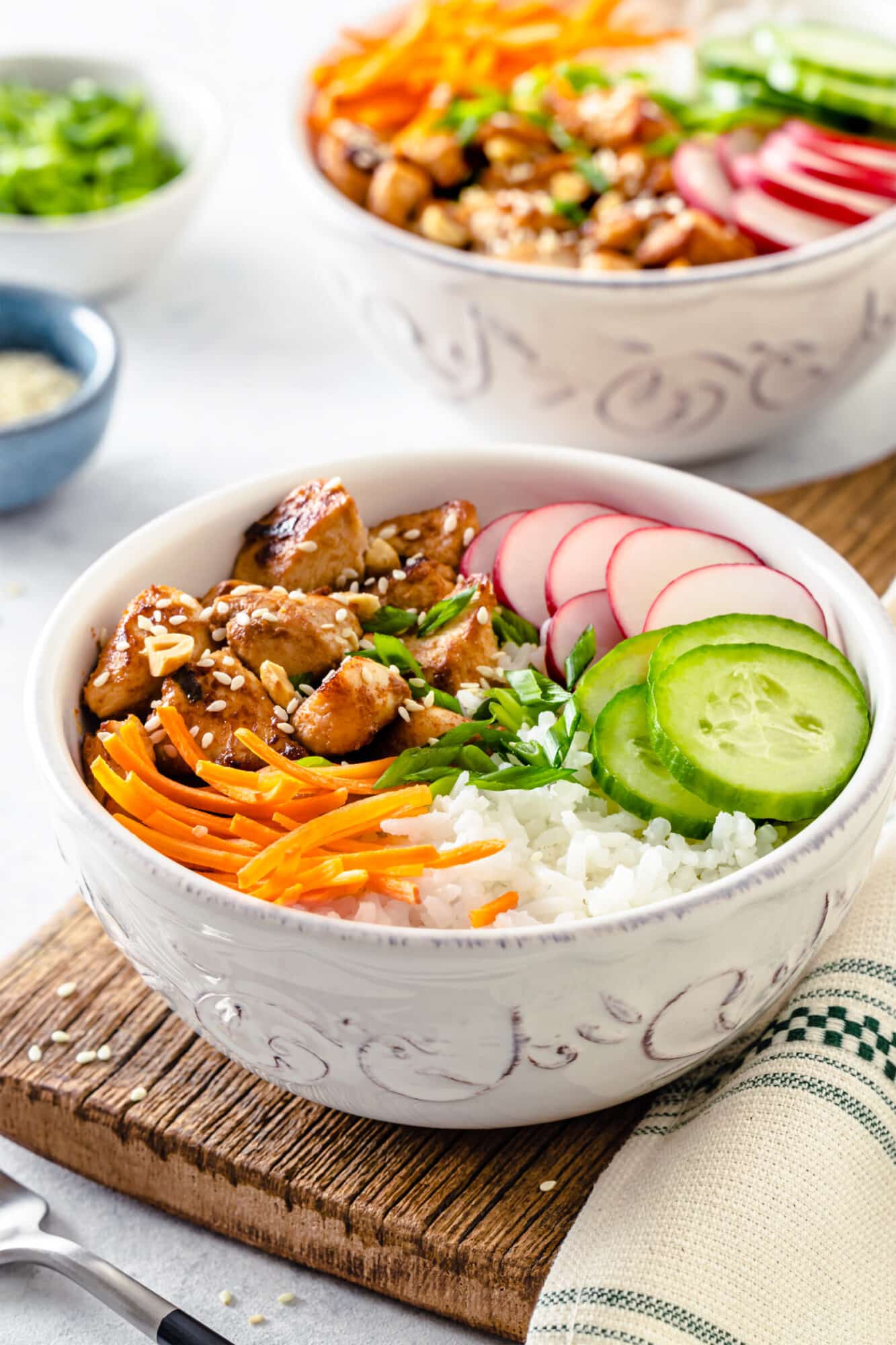 Easy Chicken Rice Bowls with Fresh Veggies Chicken rice bowl with sesame seeds on top, served in a white bowl.