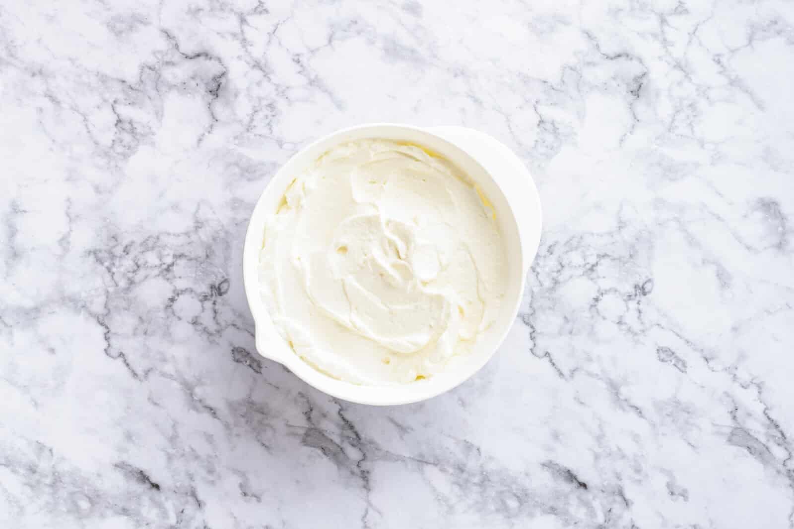 Step-by-Step Strawberry Jello Pretzel Salad Cream cheese mixed with whipping cream and sugar in a white bowl.