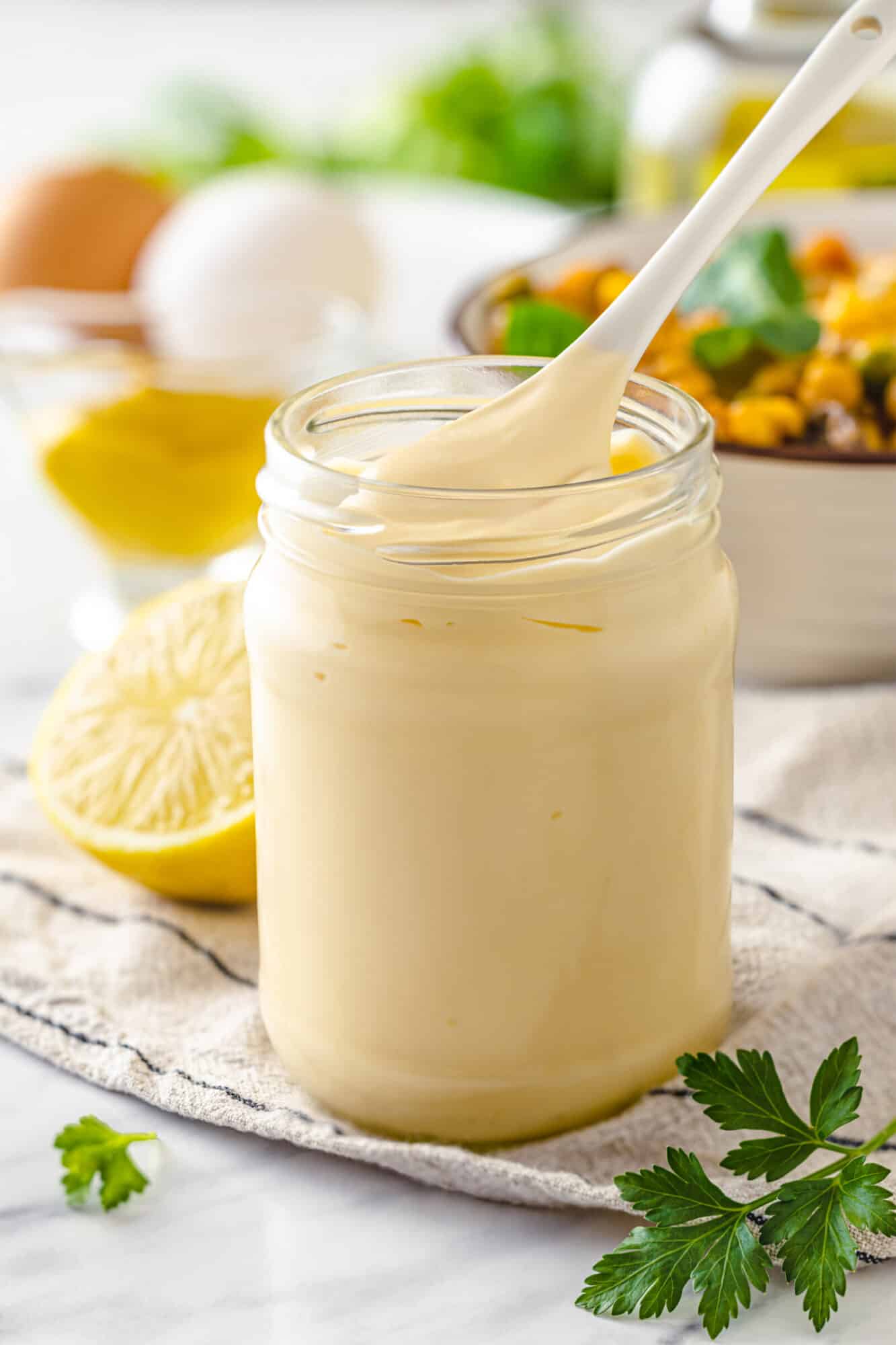How to Make Mayonnaise From Scratch Creamy mayonnaise in a glass jar with a spoon.