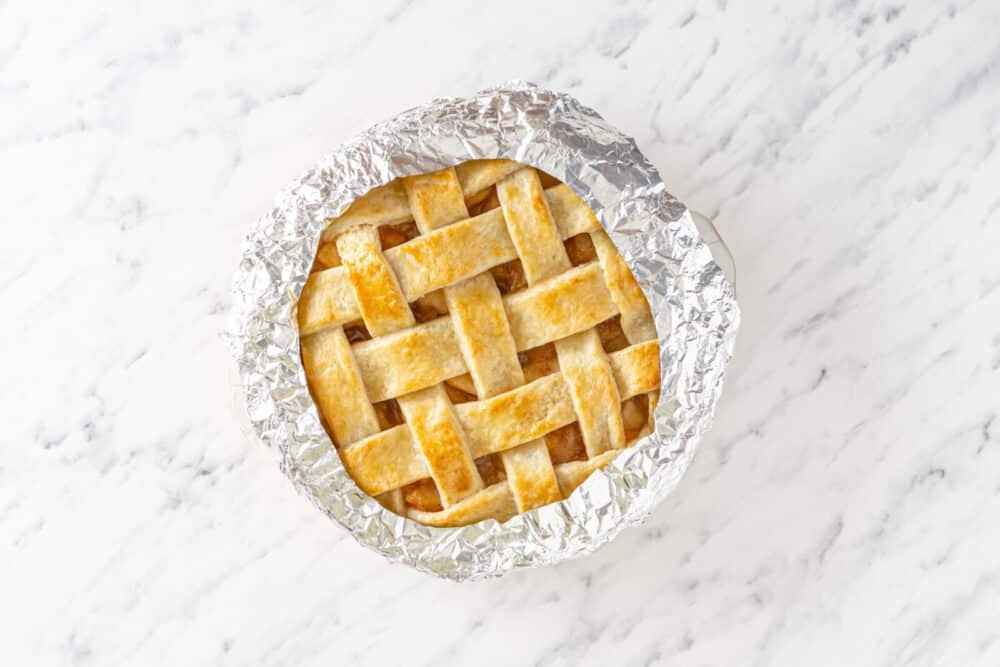 Crust edges wrapped in foil, baked fresh out of the oven pie with a lattice topping.