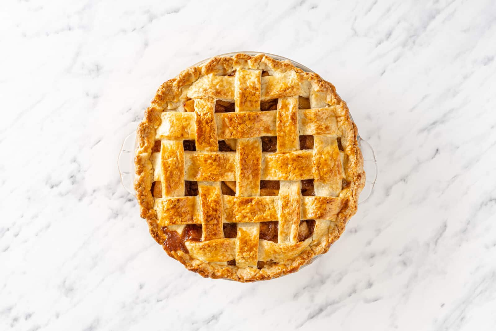 Freshly baked apple pie in a glass pie tin.