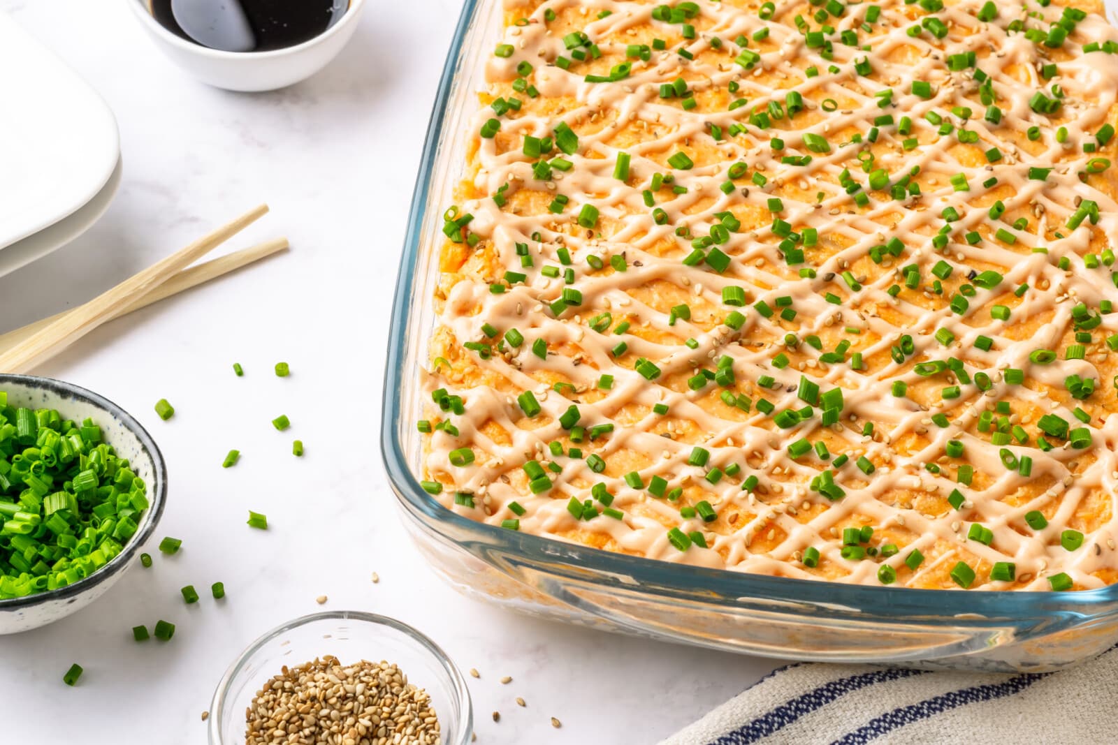Salmon Sushi Bake with Spicy Mayo Freshly baked pan of salmon sushi bake with spicy mayo, sesame seeds, and green onions on top.