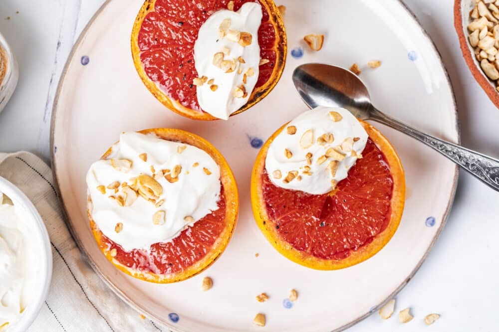 Freshly made grapefruit brûlée atop a plate with a spoon.