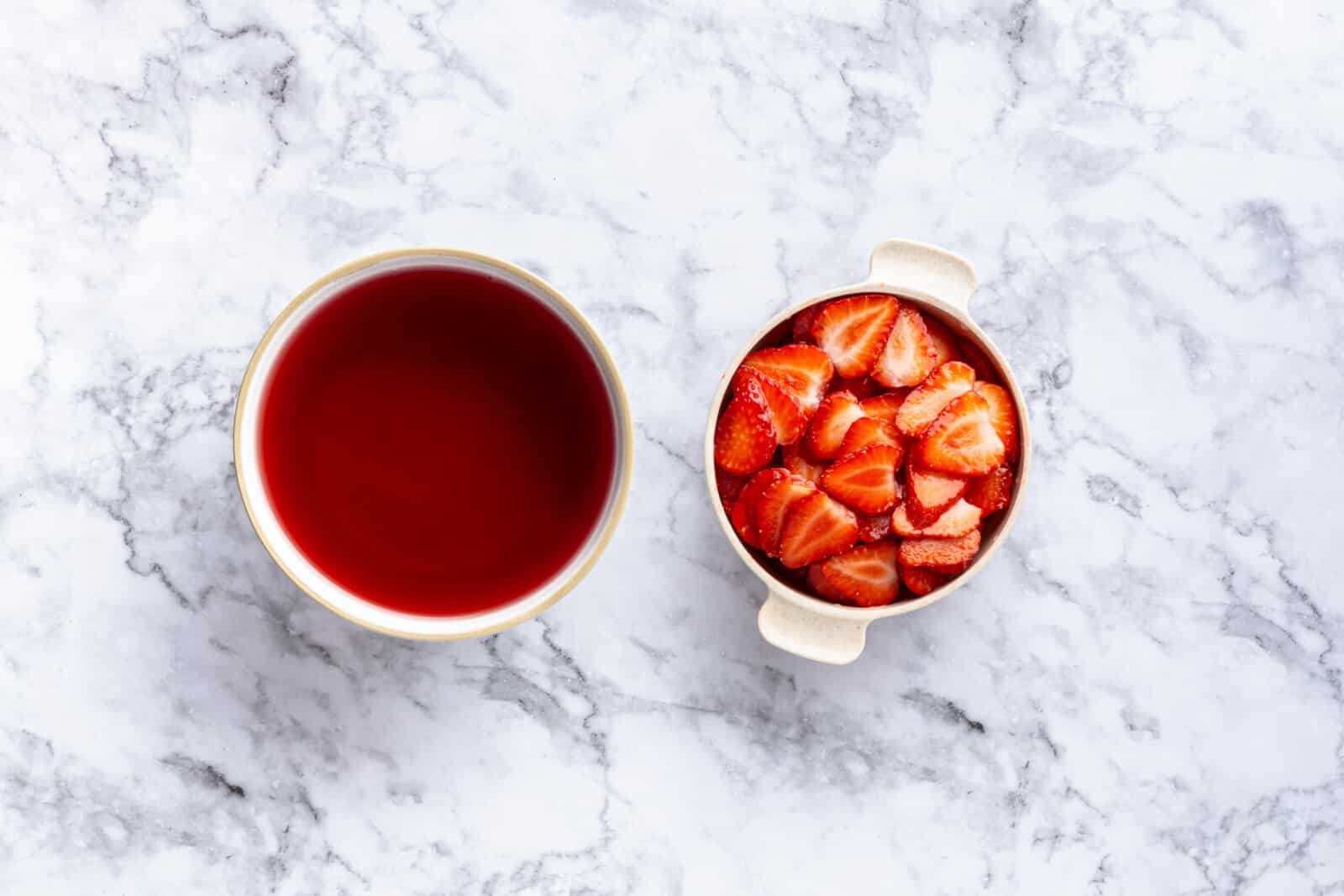 Step-by-Step Strawberry Jello Pretzel Salad Jello in a white bowl with sliced strawberries in a white bowl with handles.