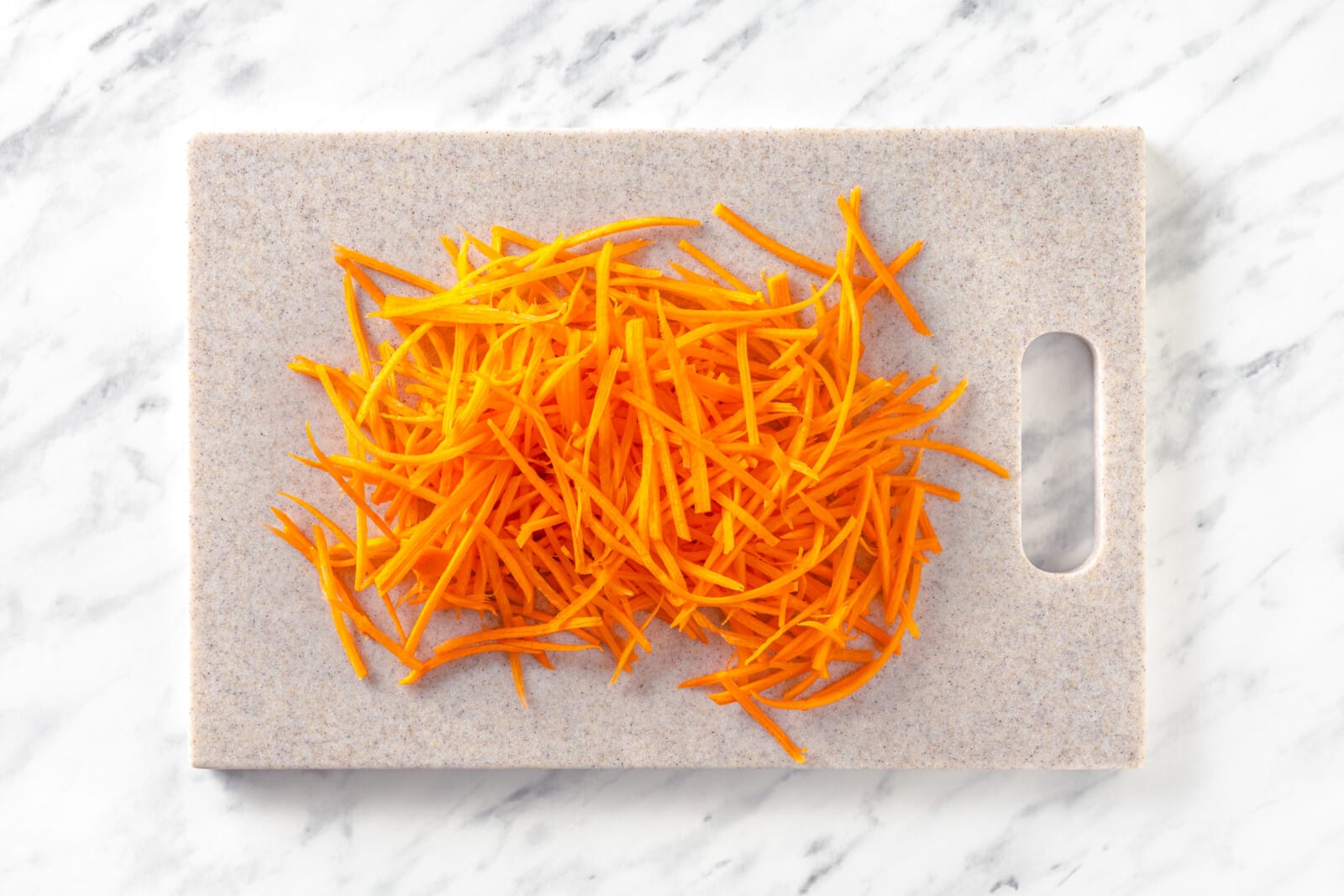 Julienned carrot on a grey cutting board.