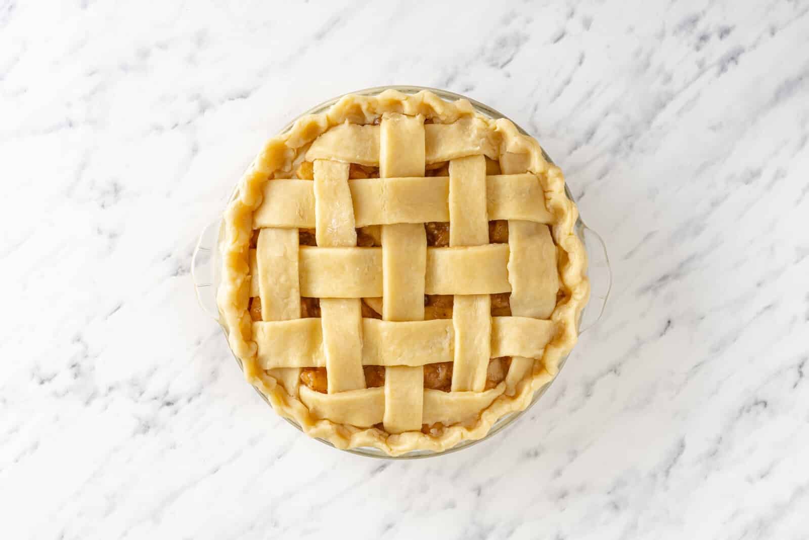 Latticed pie ready to bake in a pie tin.