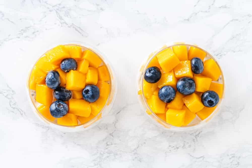 Mango and blueberries layered atop overnight oats and fruit.