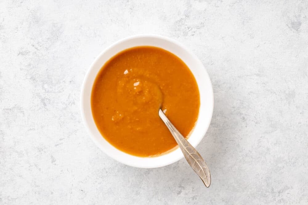 Miso pasted mixed with hot dashi in a white bowl with a spoon.
