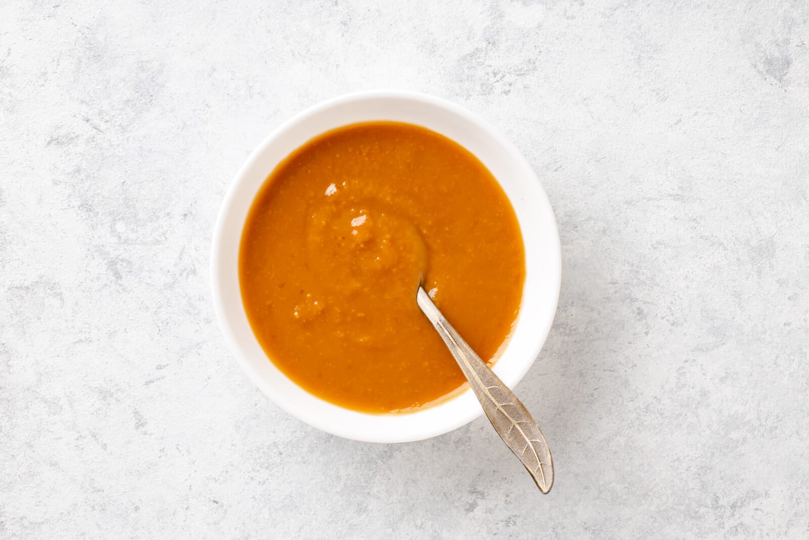 How To Make Miso Soup At Home Miso pasted mixed with hot dashi in a white bowl with a spoon.