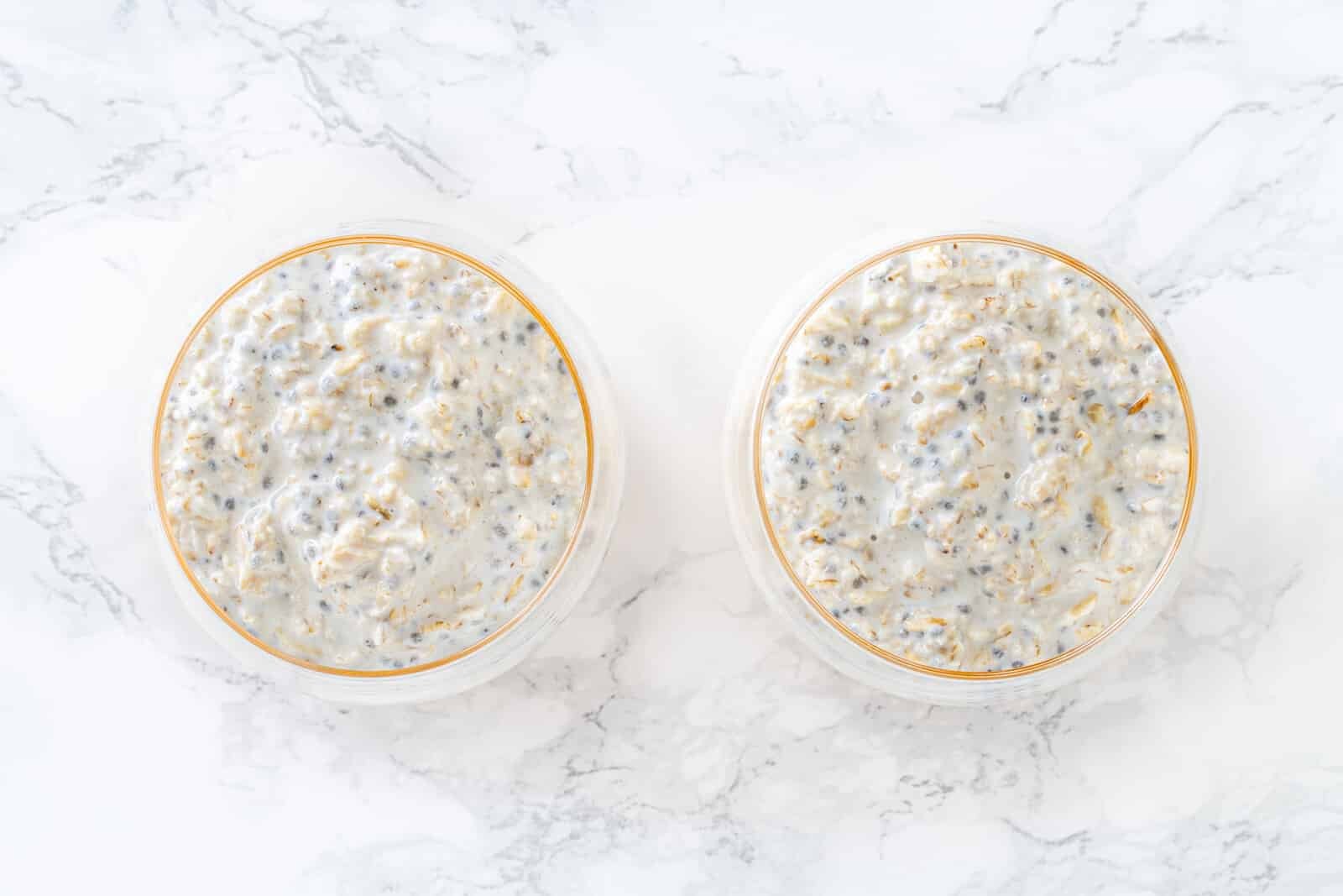 Overnight oats layered over mango cubes in glasses.