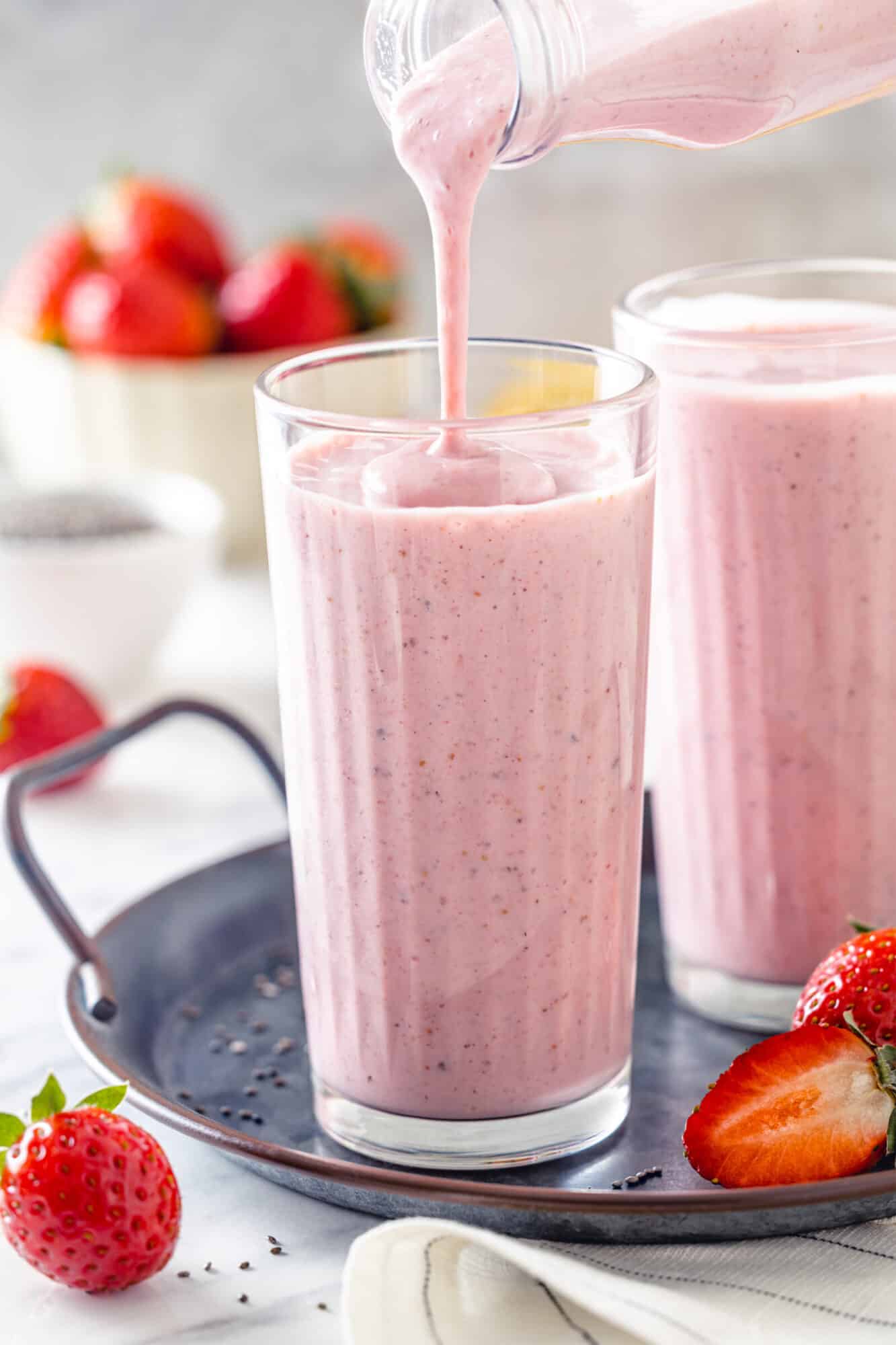 Pouring strawberry smoothie into a glass.
