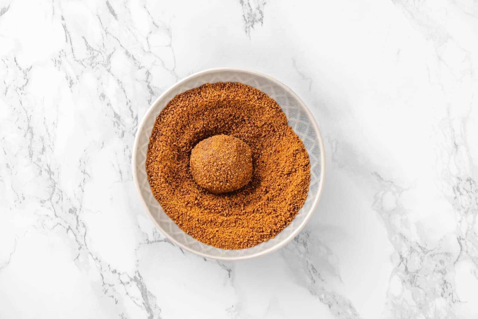 Rolled cookie dough put into the coconut sugar for coating.