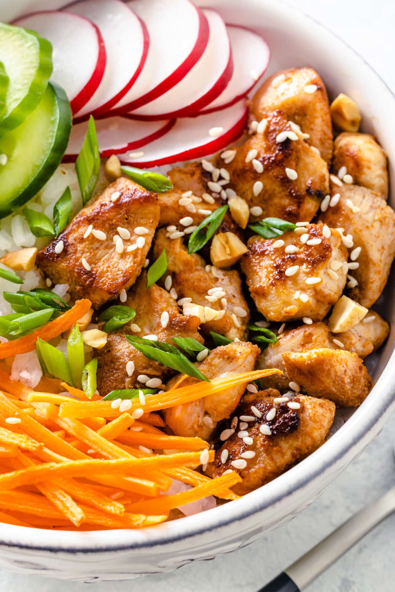 Easy Chicken Rice Bowls with Fresh Veggies Serving chicken rice bowl garnished with sesame seeds.