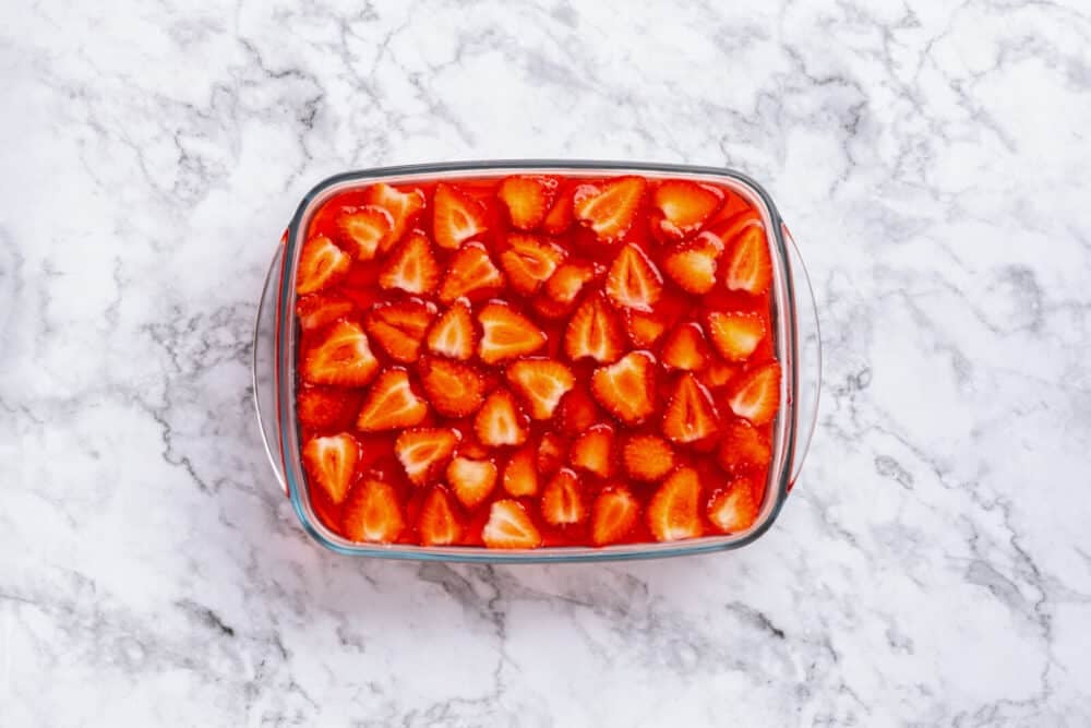 Strawberry and jello layer in a glass baking dish.