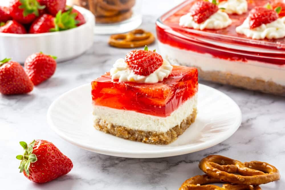 Strawberry Jello Pretzel Salad piece with a strawberry and more pretzels on the side for decor.