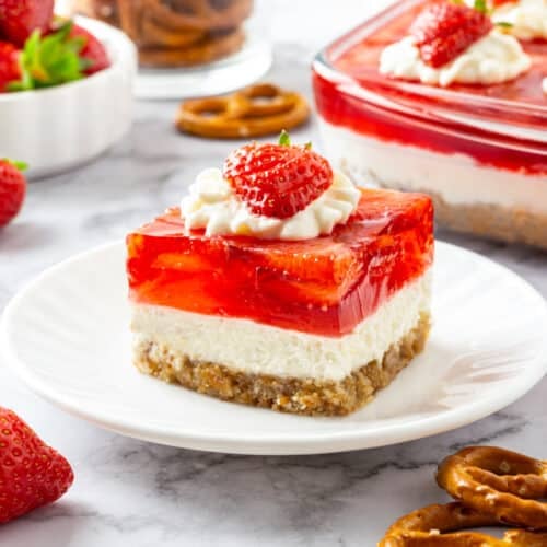 Strawberry Jello Pretzel Salad piece with a strawberry and more pretzels on the side for decor.
