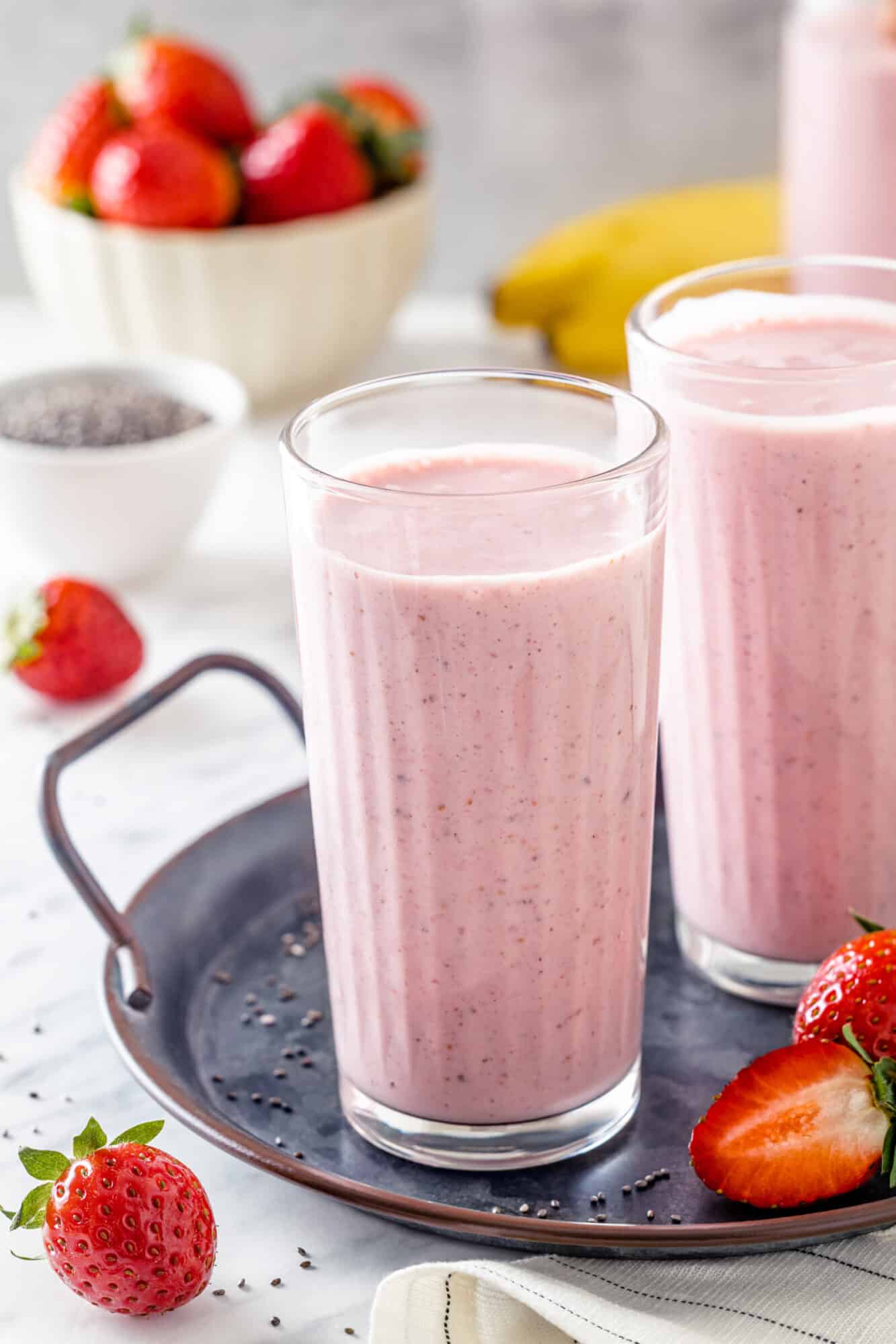 Tasty strawberry smoothie in a glass with more strawberries.