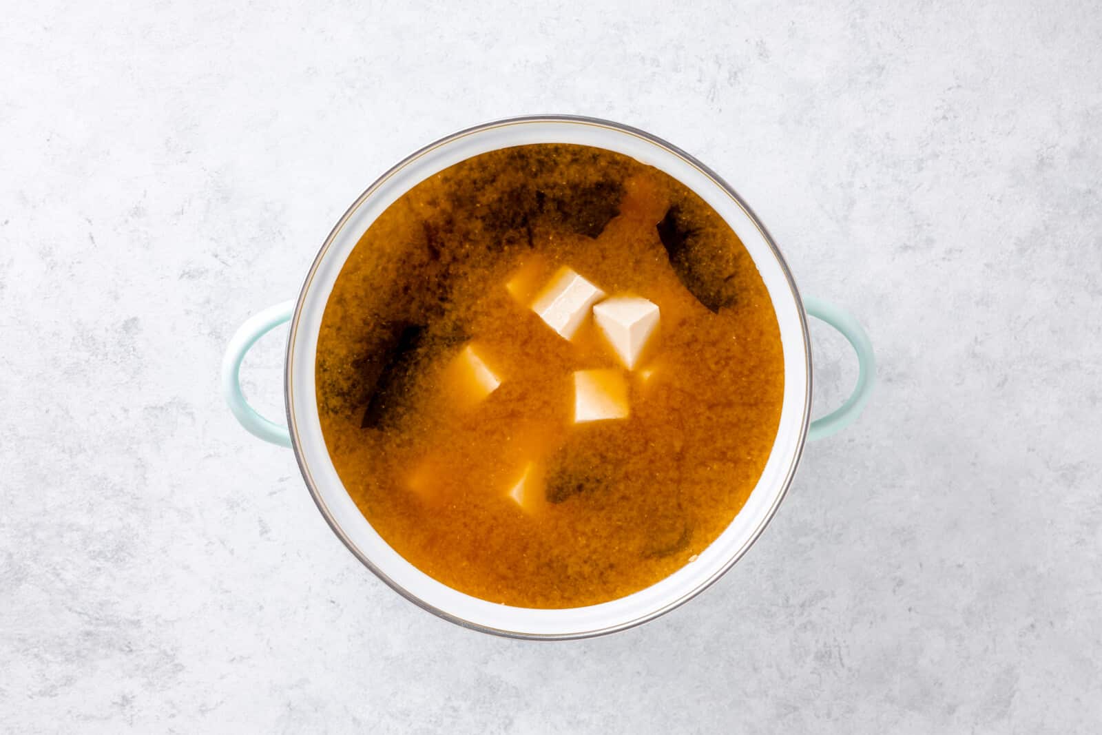 How To Make Miso Soup At Home Tofu cooking in the miso soup in a large pot.
