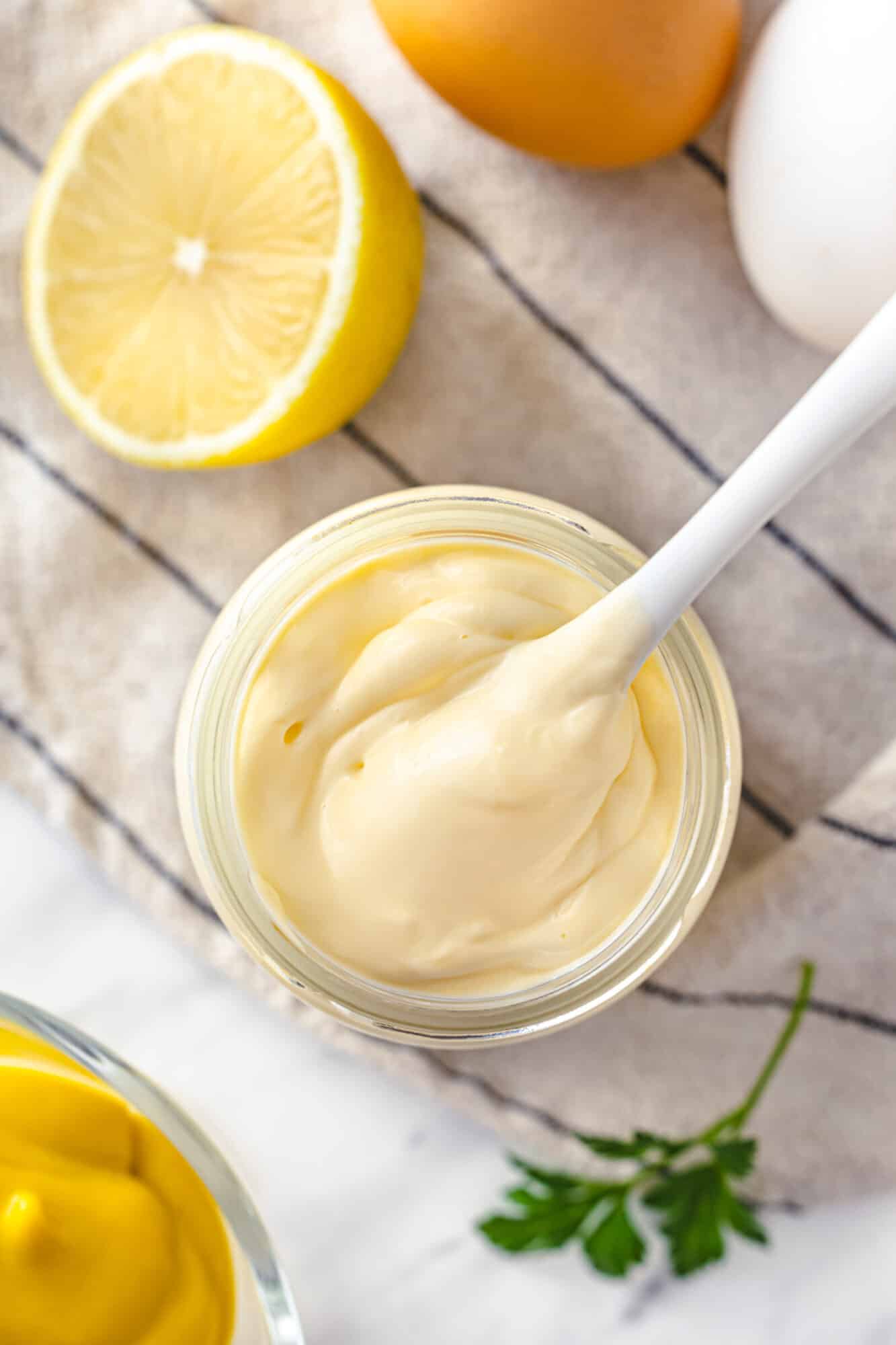 How to Make Mayonnaise From Scratch Top view of mayonnaise in a jar with a spoon.